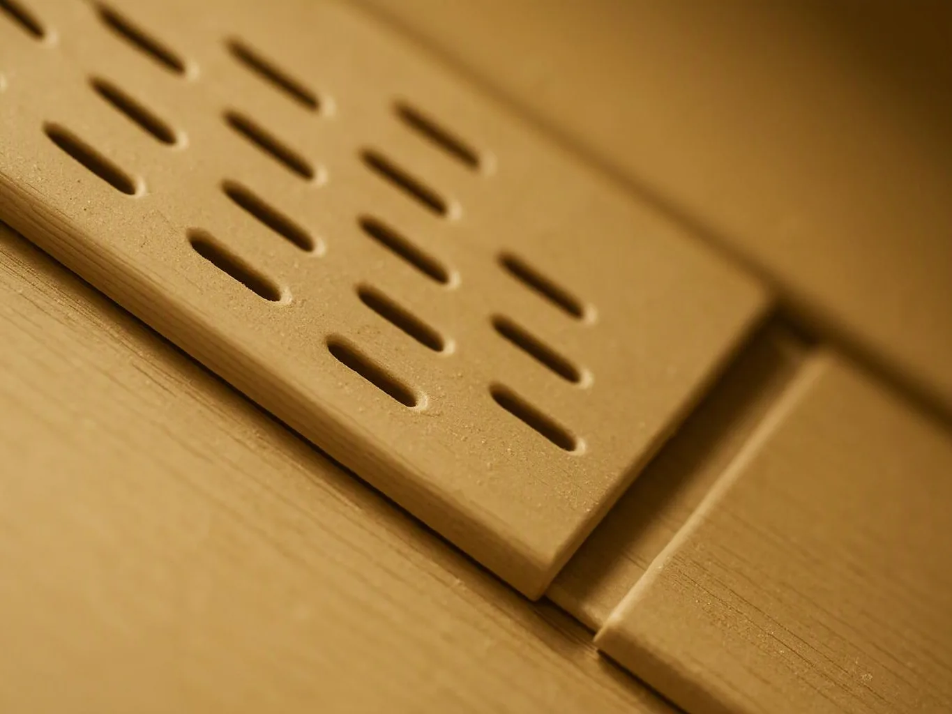 Close-up of a tan perforated metal panel resting on a matching surface