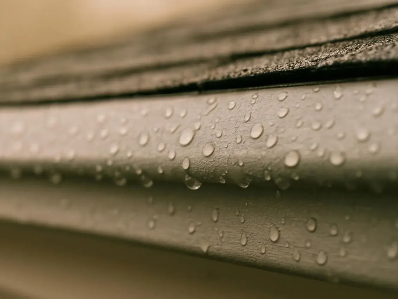 Close-up of a wet metal surface with water droplets under a dark textured edge